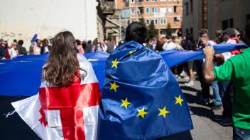 En kvinde med Georgisk flag svøbet om sig, en mand med EU flag svøbet om sig 