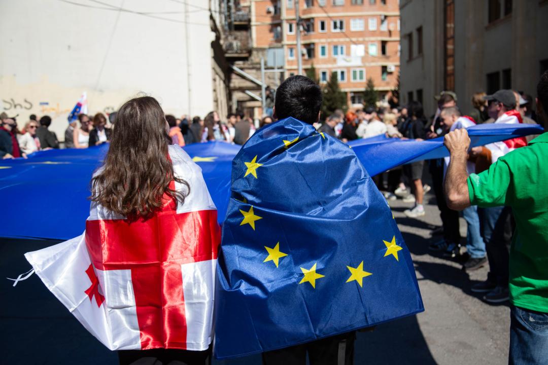 En kvinde med Georgisk flag svøbet om sig, en mand med EU flag svøbet om sig 