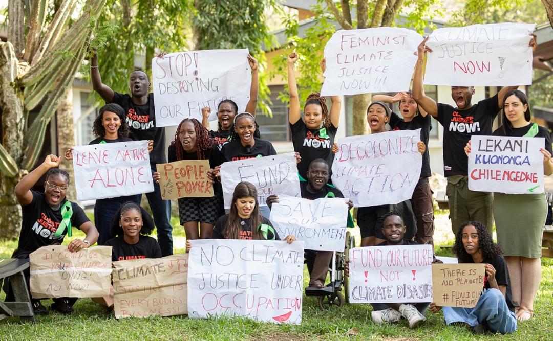 Unge klimaaktivister under deres deltagelse i Climate Justice Academy, hvor de står sammen i et gruppefoto med skilte hver især som de selv har lavet. Skiltene har klima budskaber på dem.